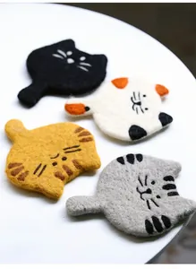 Detail of four handmade wool felt cat coasters showing texture and cute embroidery