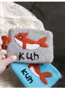 Macro shot of handmade wool felt coin purse with embroidered fish pattern and kun text