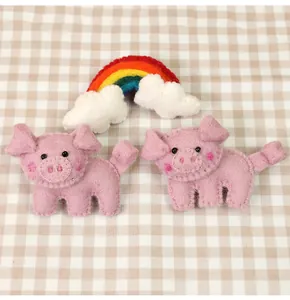 Close-up of handmade pink wool felt pig brooches with fine stitching and soft texture