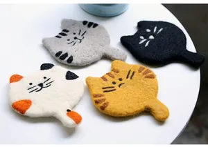 Detailed close-up showing textured wool felt material and cute embroidered cat coasters