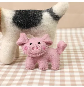 Detail of pink handmade wool felt pig brooch with soft texture and delicate stitching