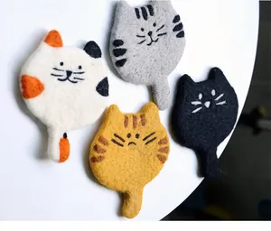 Macro shot of handcrafted wool felt cat coasters showing soft texture and detailed fibers