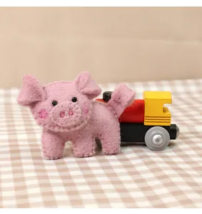 Close-up of handmade pink wool felt pig brooch featuring black bead eyes and cute snout