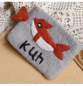 Detail of grey wool felt coin purse with orange whale embroidery and KUN text