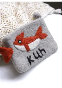 Detail of grey wool felt coin purse with red whale embroidery and kuh text on knit fabric