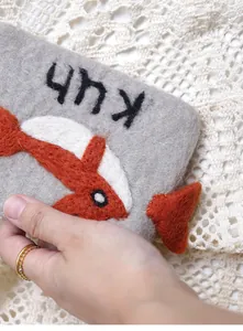 Macro shot of handmade grey wool felt coin purse with red koi fish needlework detail
