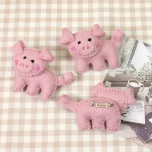 Handmade pink wool felt pig brooch featuring cute piglet faces and silver metal pin backs