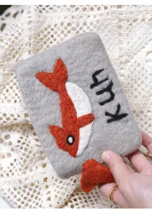Close-up of handmade gray wool felt coin purse with orange fish and Kuh embroidery