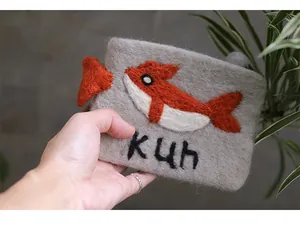 Macro shot of grey wool felt coin purse featuring a whale patch and embroidered kuh logo