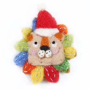 Handmade lion wool felt brooch with colorful mane and Christmas hat on white background