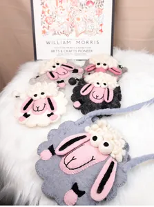 Détail de pochettes mouton en feutre fait main en plusieurs couleurs sur fond en peluche