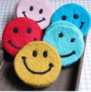 Close-up of colorful wool felt coasters with smile patterns on a wooden tray