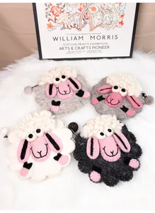 Détail de quatre porte-monnaie mouton en feutre faits main en blanc, noir et gris sur peluche