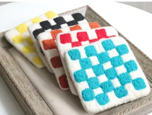 Close-up of wool felt checkerboard coasters with needle felt texture and colorful patterns