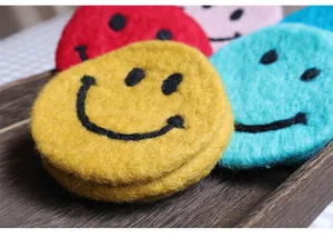 Close-up of colorful felt coasters featuring hand-stitched smiley faces on a wooden tray