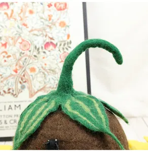 Close-up of wool felt leaf texture and green stem detail on top of a handmade brown hat