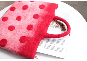 Detail of pink felt tote with red polka dots featuring a circular handle and zip closure