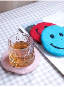 Detail of wool felt coasters with smiley face embroidery and thick insulating texture