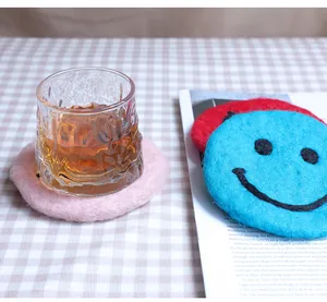 Detailed close-up of colorful wool felt coasters with cute smiley face patterns on plaid cloth
