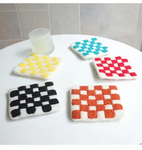Close-up of colorful checkered wool felt coasters in five colors on a white table