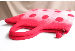 Close-up of red and white polka dot felt handbag showing fuzzy texture and pom-pom detail