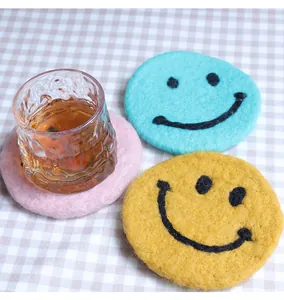 Close-up of thick felt coasters with cute embroidered smile faces in pink and blue