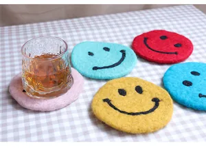Close-up of colorful handmade wool felt coasters with cute smiley faces on checkered fabric