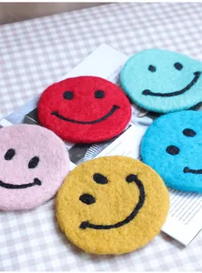Close-up of colorful round wool felt coasters with smiley face design on a table