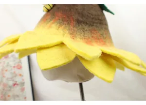 Close-up of handmade sunflower wool felt hat with small bee and green leaf detail