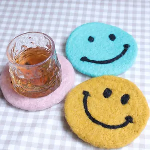 Cute smile face wool felt coasters set with glass cup on minimalist checkered tablecloth