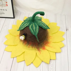 Cute sunflower wool felt hat with green leaves and a small bee on white floor