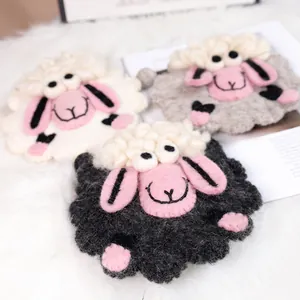 Dessous de verre mignons en feutre de laine agneau, blanc, gris et noir sur fond en peluche