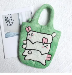 Detailed texture of green wool felt handbag with three cute white cartoon bunny motifs