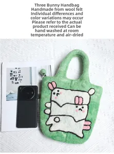 Detail of handmade green wool felt bag featuring cute white rabbit character pattern