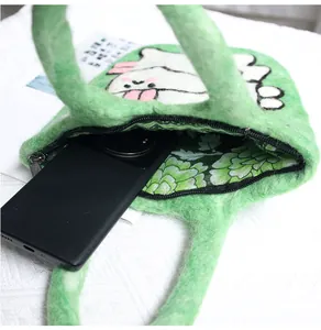 Detail of green handmade wool felt bag with cat pattern showing phone storage capacity