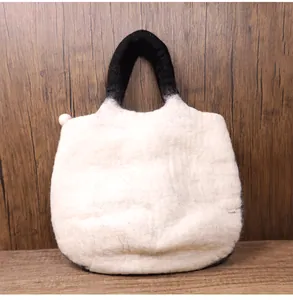 Detailed view of handmade wool felt tote bag featuring black handles and a white body