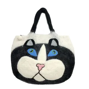 Detail of handmade felt tote bag featuring an anthropomorphic black and white cat face