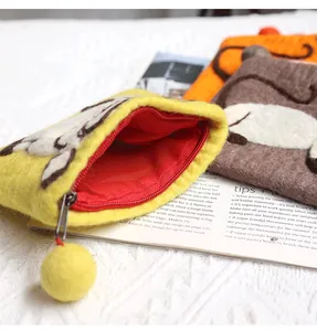Close-up of handmade wool felt animal coin purses with zipper and pompom detail