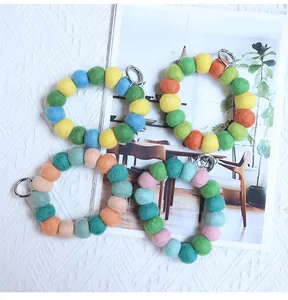 Colorful felt ball keychain rings with silver spring clasps shown on a book background