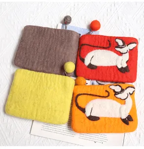 Close-up of handmade wool felt pouches with cat motifs and colorful pom-poms
