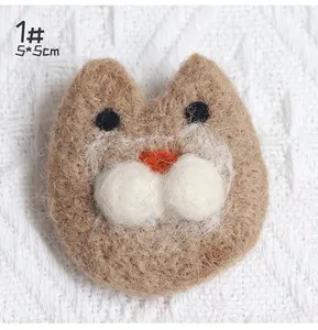 Close-up of handmade 5x5cm wool felt cat brooch pin with soft white knitted background