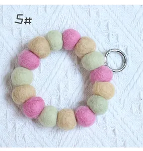 Detail of colorful pink, green and yellow wool felt ball wristlet with silver metal ring