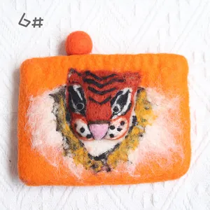 Detailed view of handmade orange wool felt coin purse with 3D tiger face and fuzzy pom pom
