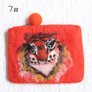 Detailed close-up of handmade red wool felt tiger head coin purse with orange pom-pom zipper