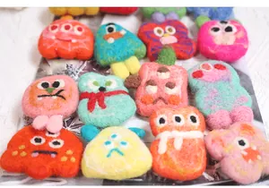 Detail showing a colorful collection of handmade felt monster brooches in various colors