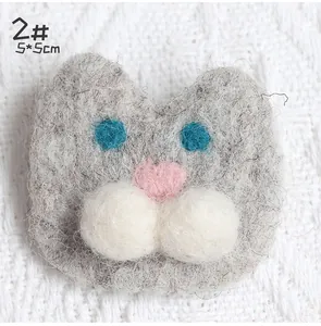 Close-up of handmade gray felt cat brooch with blue eyes and pink heart nose