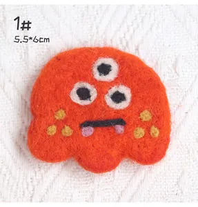 Detail shot of a 5.5x6cm orange wool felt monster brooch with high quality plush texture