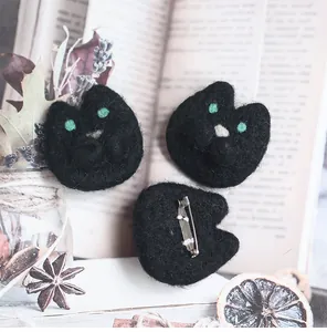 Detail of handmade black felt cat brooches with green eyes and metal safety pins