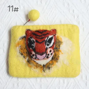 Detailed close-up of wool felt tiger coin purse with a yellow pom-pom zipper pull