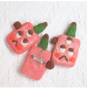 Detail of pink wool felt monster brooches with secure metal pin backings on lace